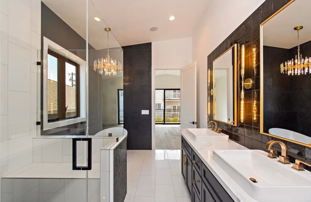 Maple Residence bathroom with freestanding tub, glass shower, dark tile, brass fixtures, and double vanity.
