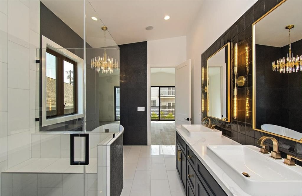 Maple Residence bathroom with freestanding tub, glass shower, dark tile, brass fixtures, and double vanity.