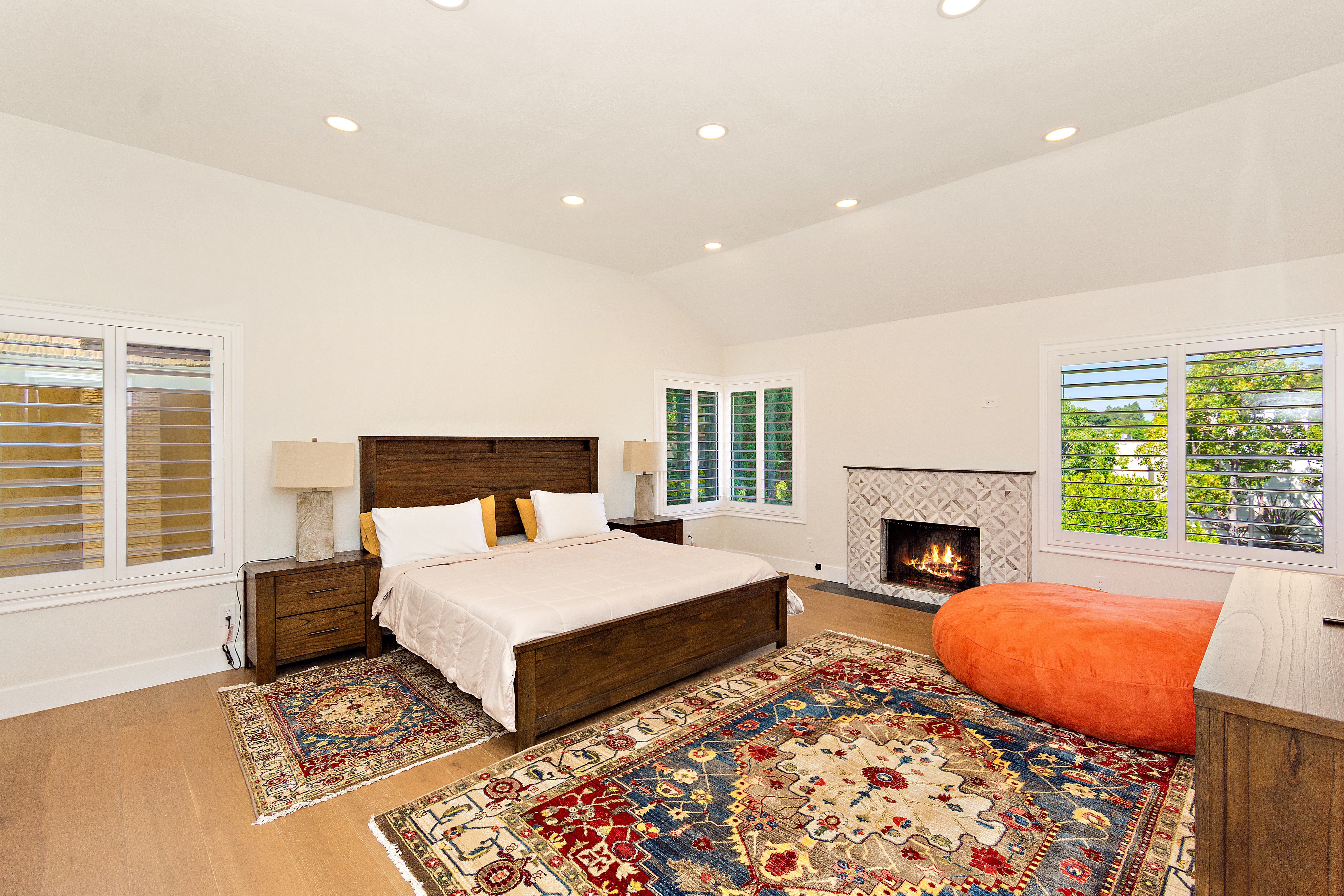 Rainstar Residence primary bedroom with warm wood tones, soft light, fireplace, and calm neutral styling.