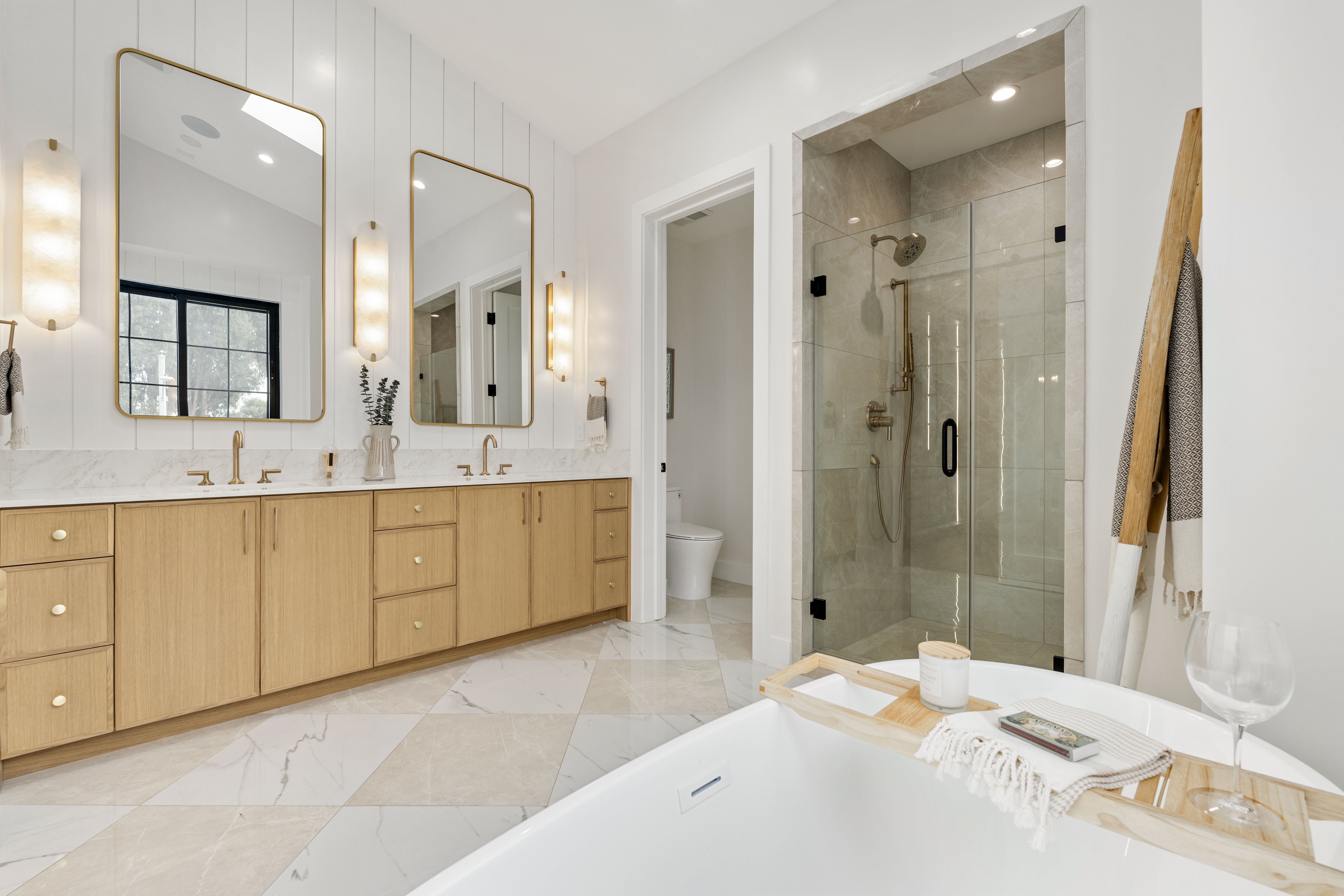 Magnolia Residence bathroom with a long vanity, glass shower, warm accents, and bright modern finishes.