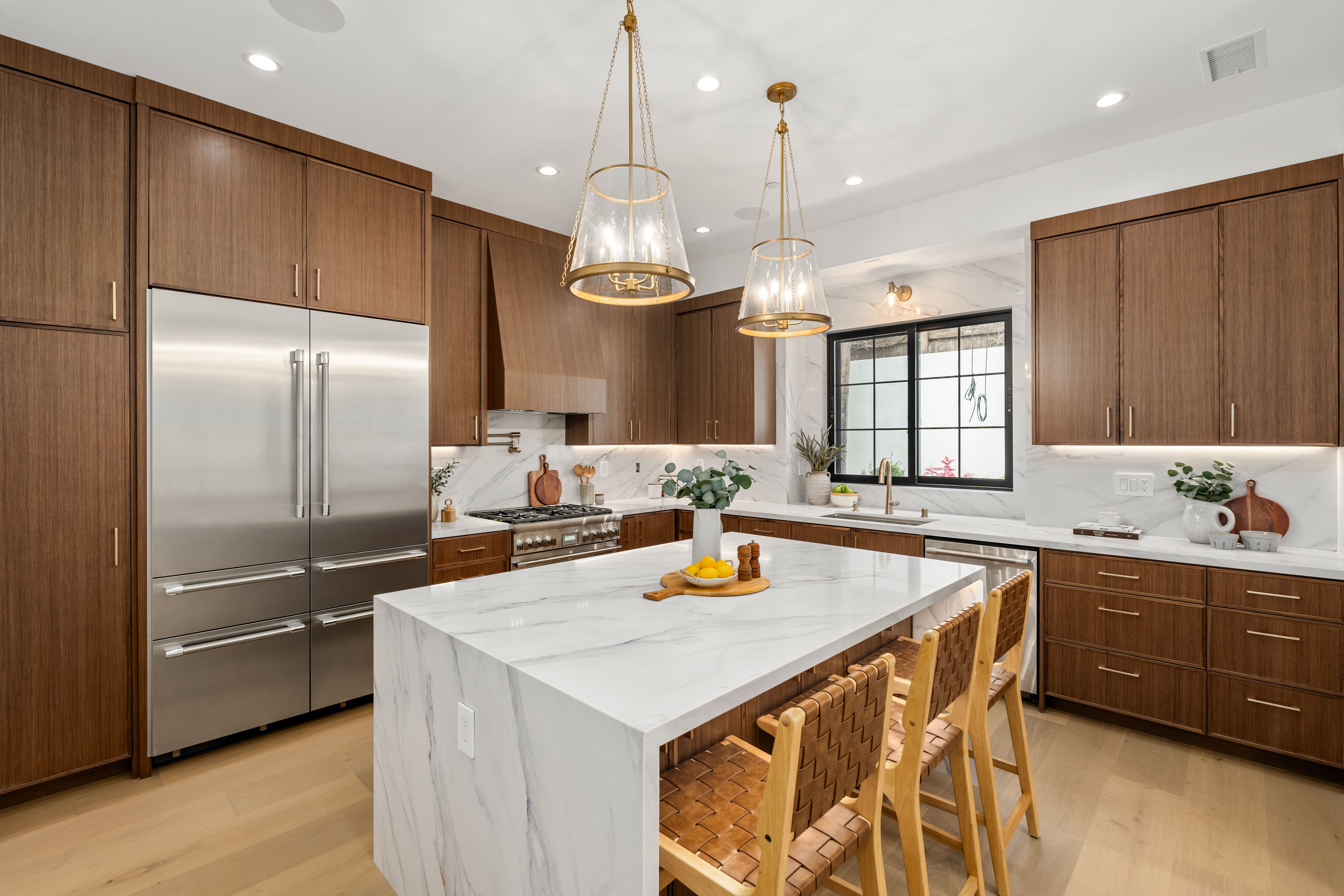 Magnolia Residence kitchen with warm cabinetry, a large island, statement pendant lighting, and open living flow.