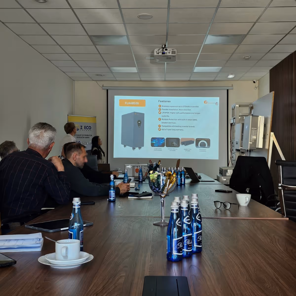 Prezentacja magazynu energii model FLA48500 podczas szkolenia w siedzibie Z-Ecoenergy. Na ekranie wyświetlone są parametry baterii LiFePO4, w tym skalowalność i długa gwarancja.