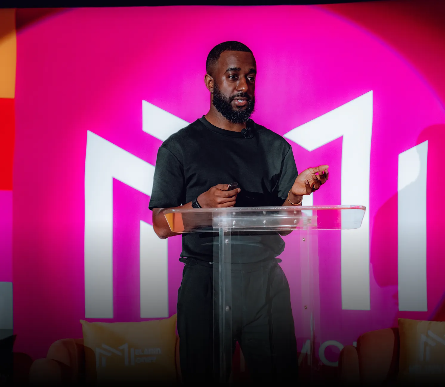 Codner presents business coaching and advice on stage, explaining wealth building strategies to entrepreneurs.