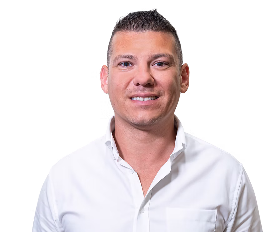 Man with short dark hair wearing a white button-up shirt, smiling against a transparent background.