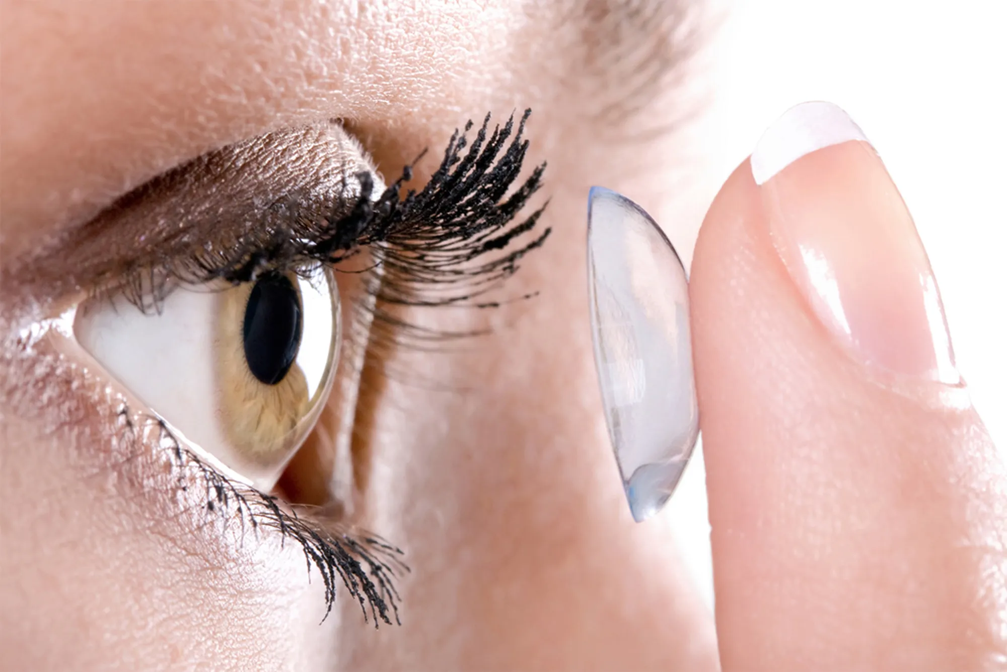 Close-up of a woman applying a soft contact lens to her eye