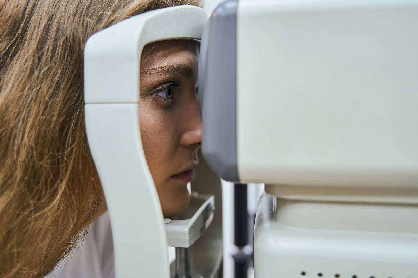 Woman positioned at a slit lamp machine during an eye examination