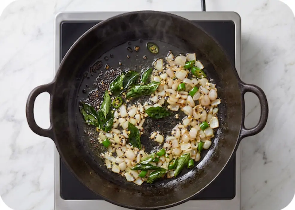 mustard seeds, the curry leaves, chopped green chillies, and chopped pearl onions