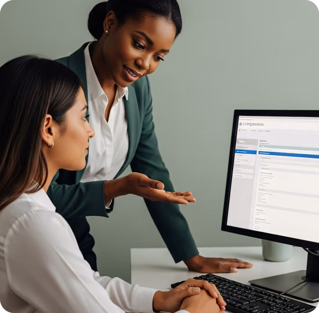 Two professional women looking at a computer monitor, with one explaining something to the other.