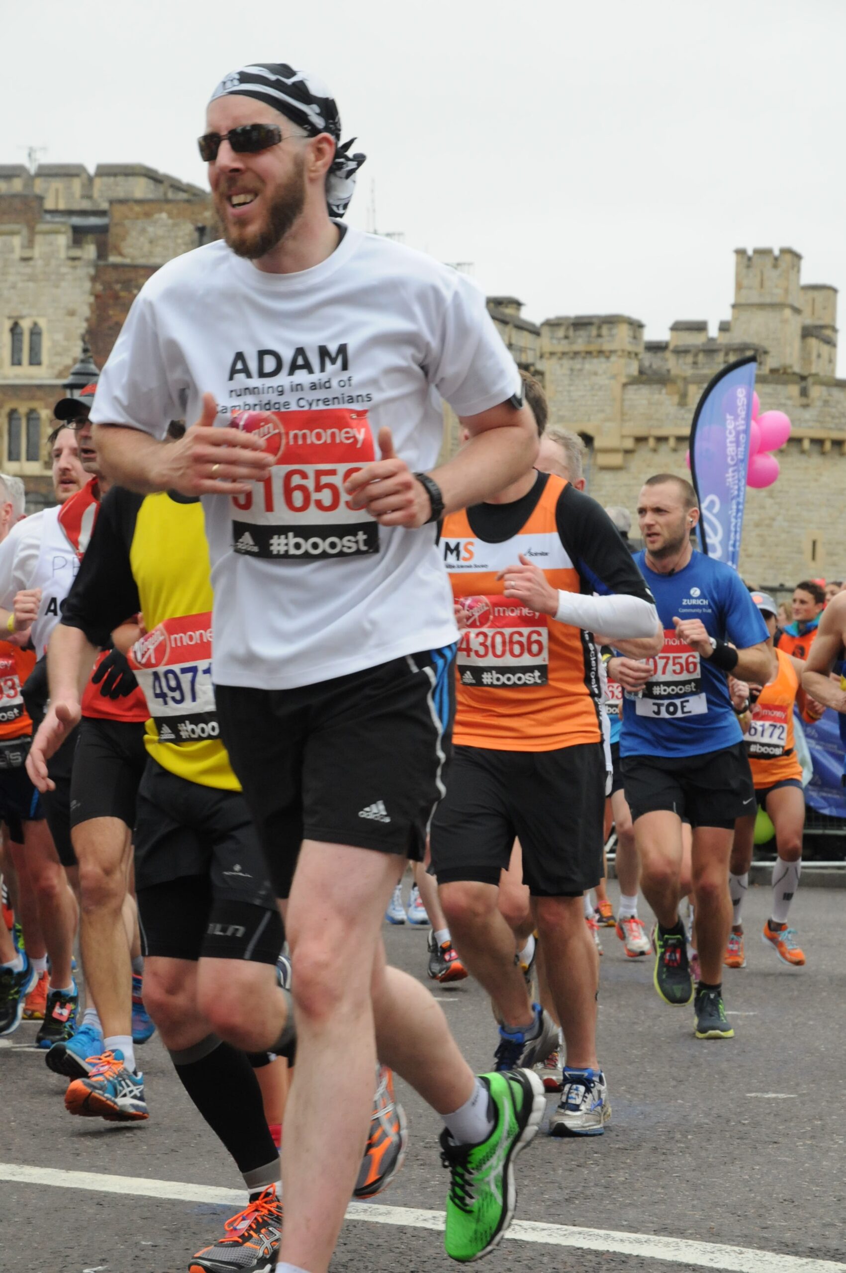 Runners participating in a road race with historic stone buildings in the background.