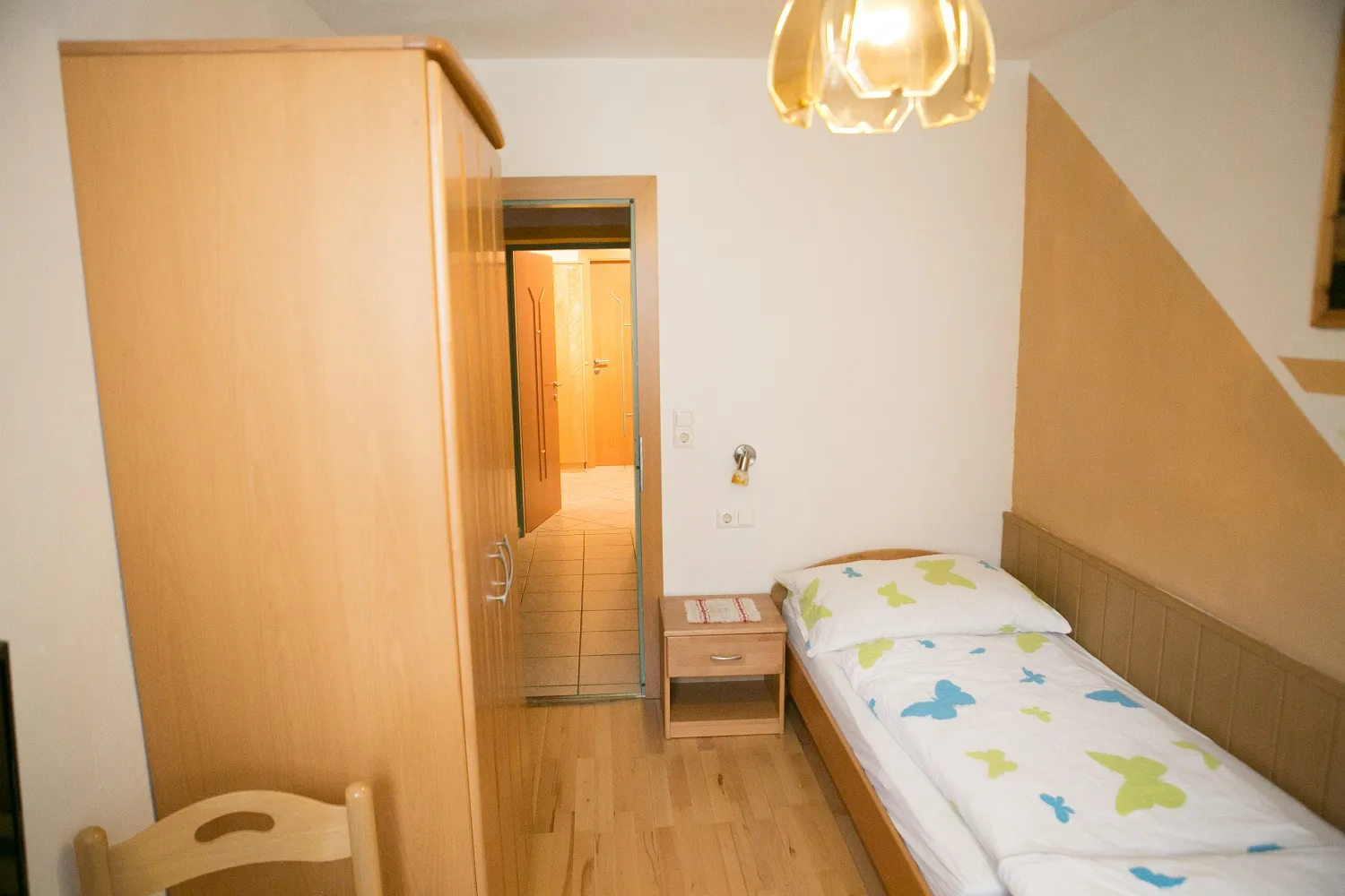 Schlafzimmer mit Einzelbett und Kleiderschrank in der Ferienwohnung Waldblick