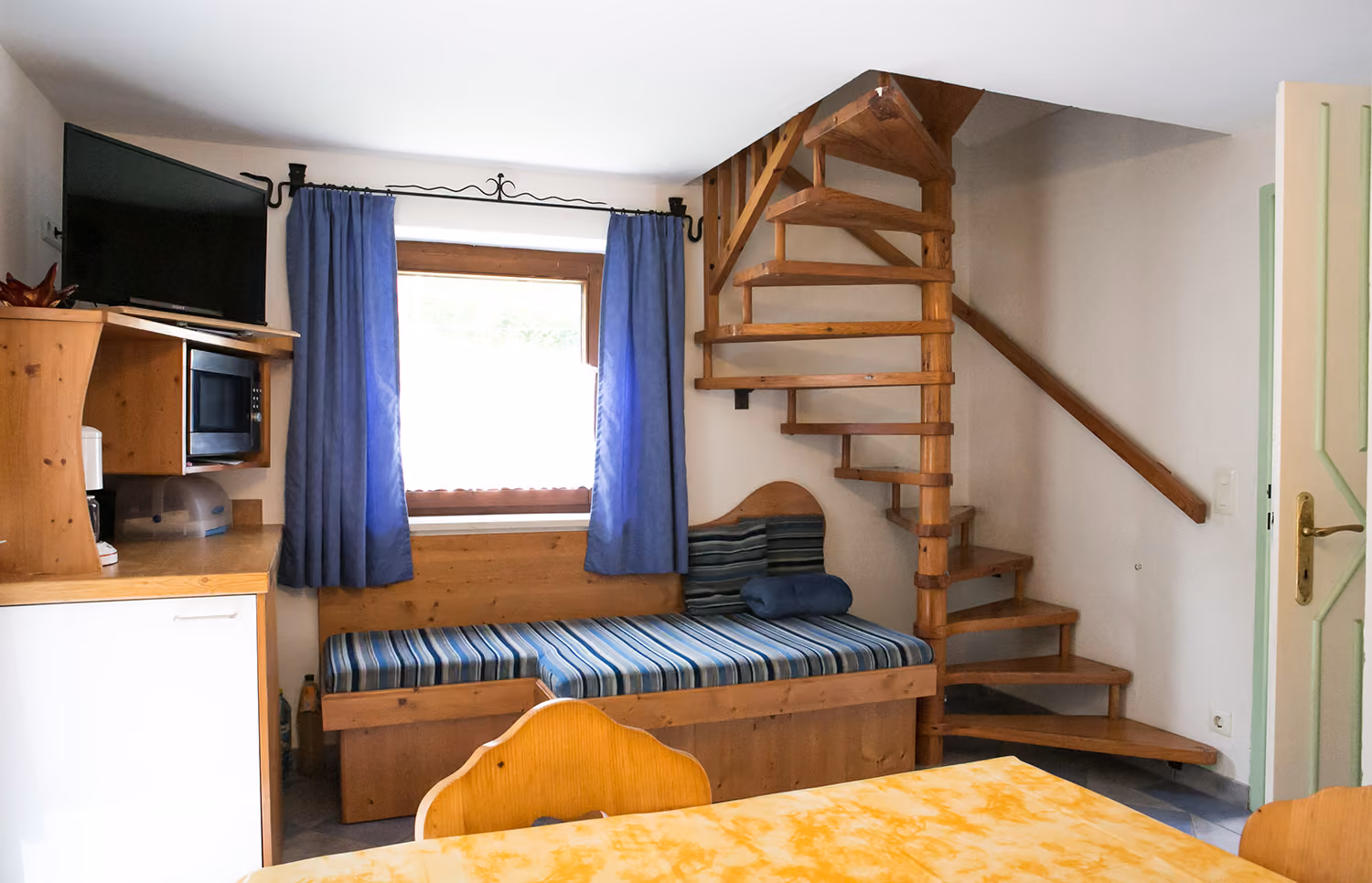 Wohnbereich mit Wendeltreppe und Sitzbank in der Ferienwohnung Teufelsgraben