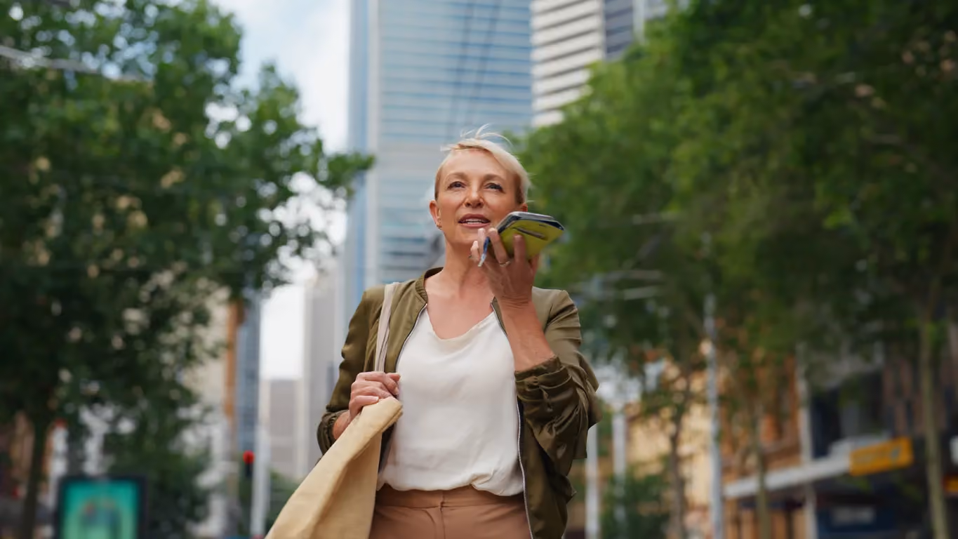 Businesswoman using AI chatbot on smartphone while walking in a U.S. city, showcasing AI agent adoption in enterprise technology.