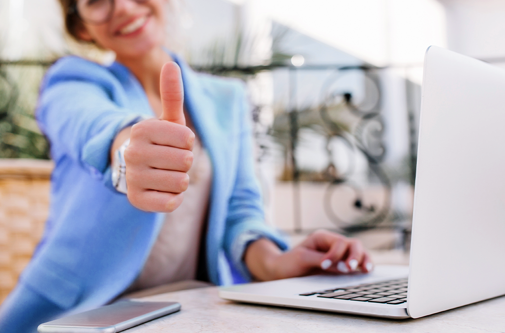 Woman sitting at her laptop with a thumbs-up 