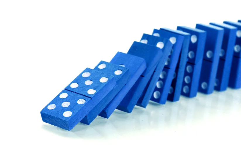 A plain white background showing a row of blue wooden dominoes toppling over in a continuous chain reaction.