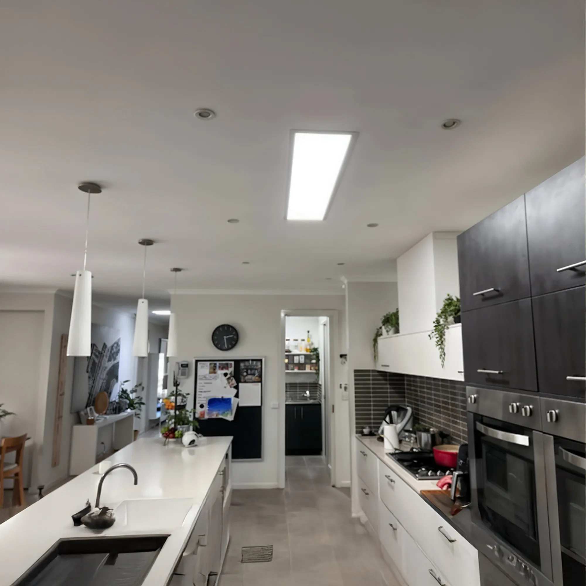Modern kitchen with a white island countertop, built-in ovens, stove, and hanging pendant lights.