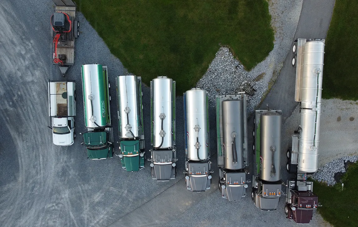 Aerial view of several tanker trucks and a white utility truck parked on gravel.