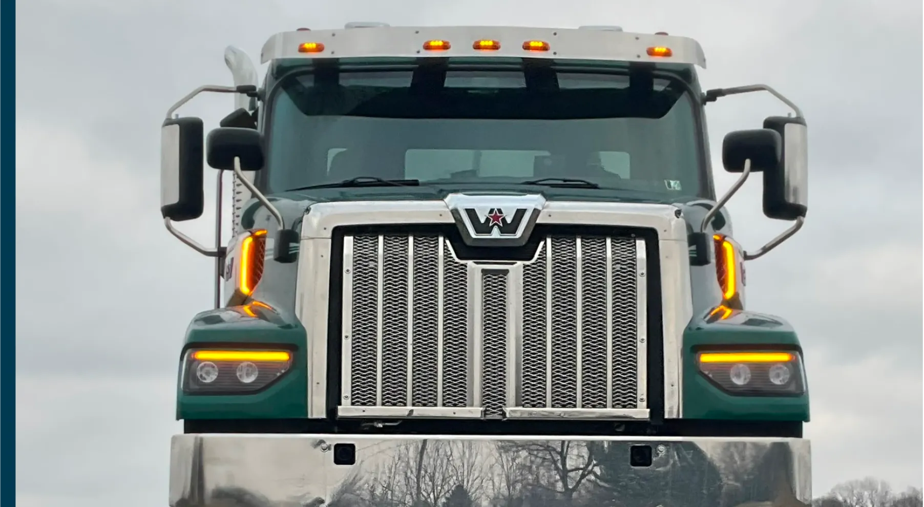 Front view of a green and silver Western Star commercial truck with illuminated amber lights.