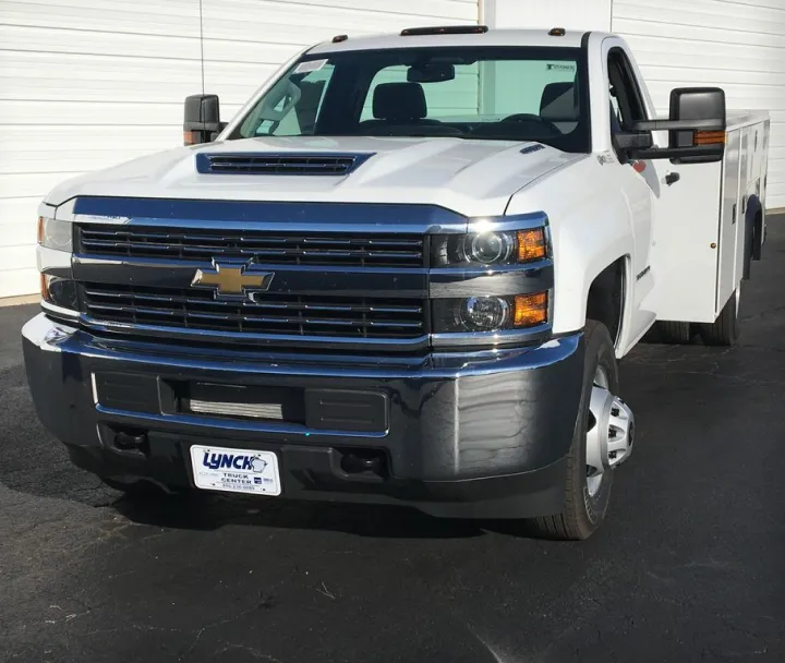 Front view of a white Chevrolet heavy-duty pickup truck parked on asphalt with a large grille and dual rear wheels.