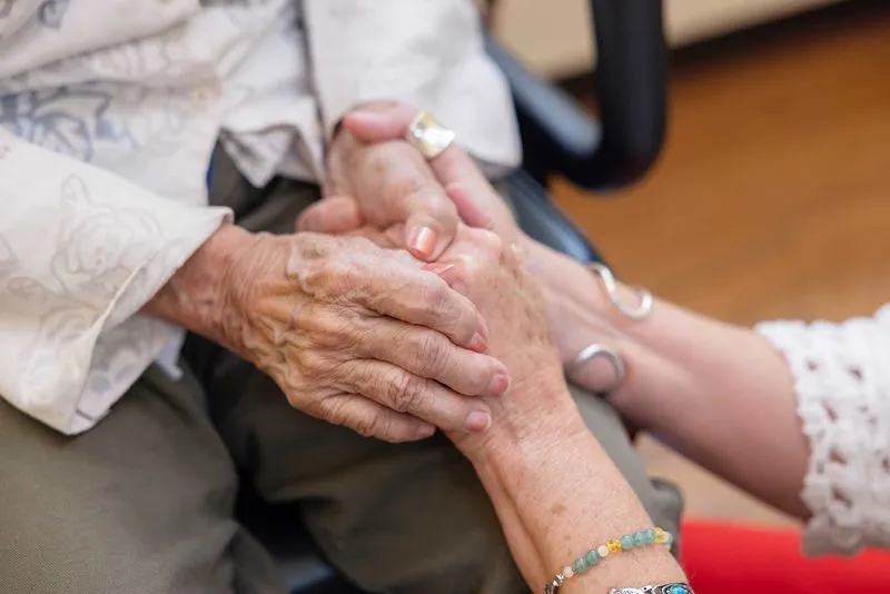 Close up of staff member holding residents hands