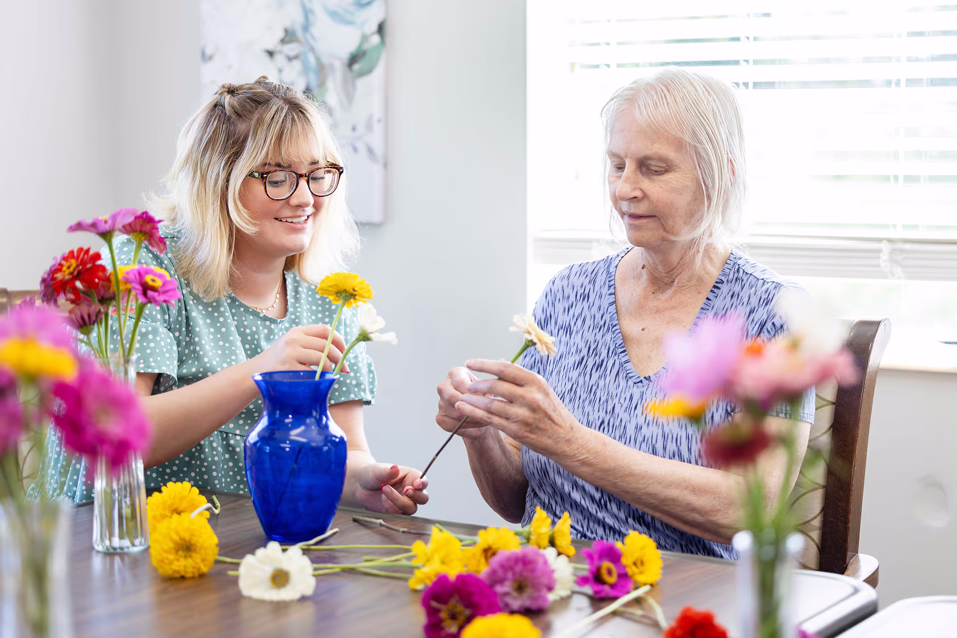 an older woman works on a flower arrangement with a younger woman
