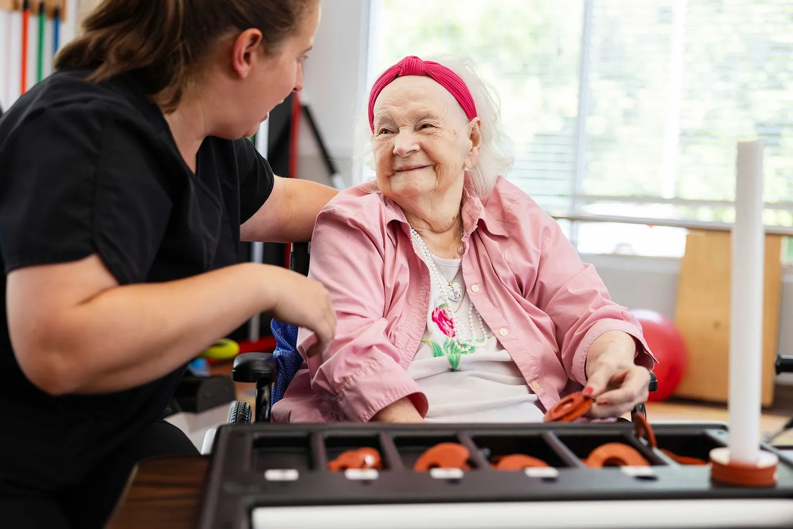 Occupational therapist and elderly woman in a wheel chair smiling at each other