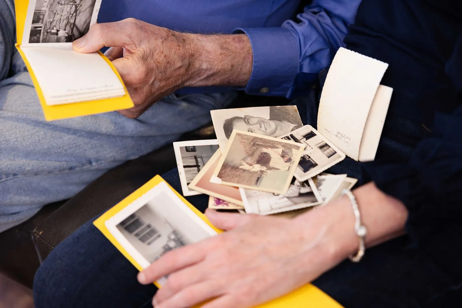 Close up of elderly man and daughter looking at old photos in her lap