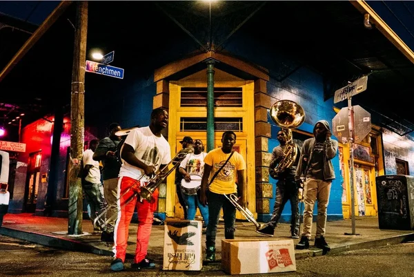 Street musicians perform together at night on a colorful New Orleans corner, illustrating how modern work operates more like collaborative jazz than