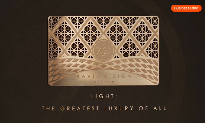 Metallic business card with geometric lattice design and text 'Xavio Design Mayfair' on black background with phrase 'Light: The Greatest Luxury of All'.