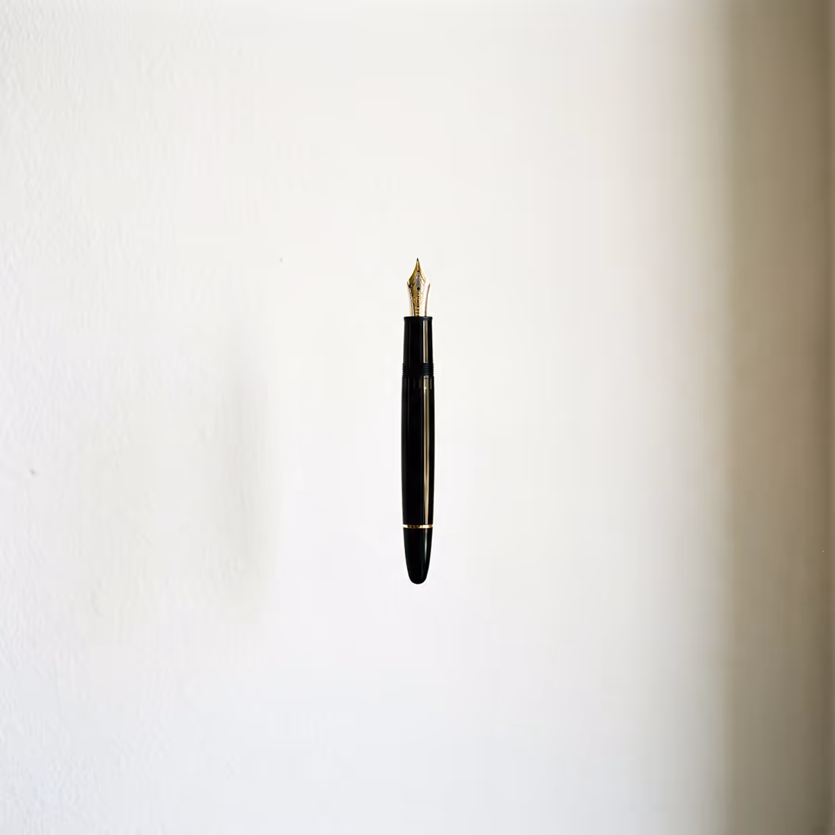 Black fountain pen with gold nib centered against a plain white background.