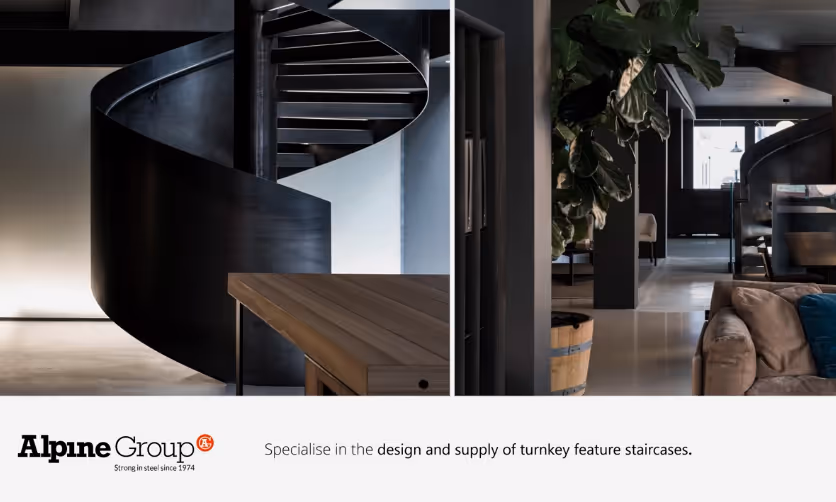 Modern black steel spiral staircase inside a sleek, contemporary interior with wooden table and seating area.