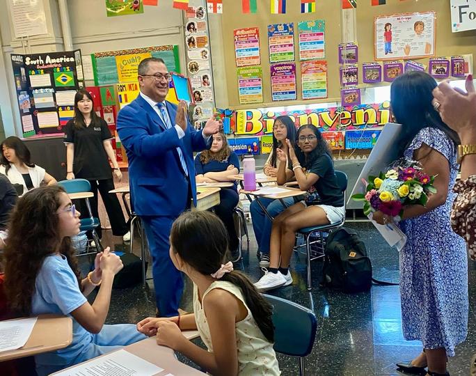 Administrator addresses students and teacher receiving flowers in classroom