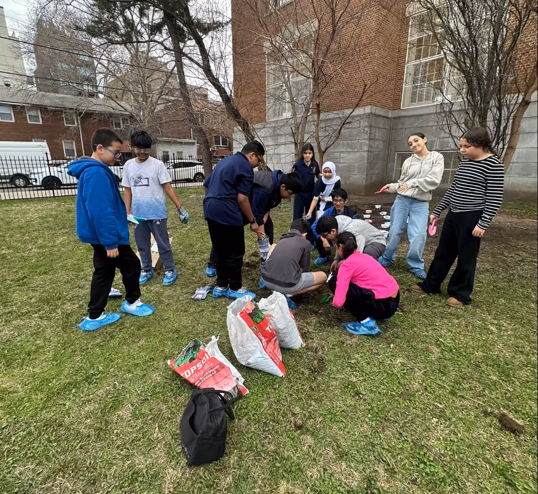 Students planting in the school wellness garden outdoors with soil bags