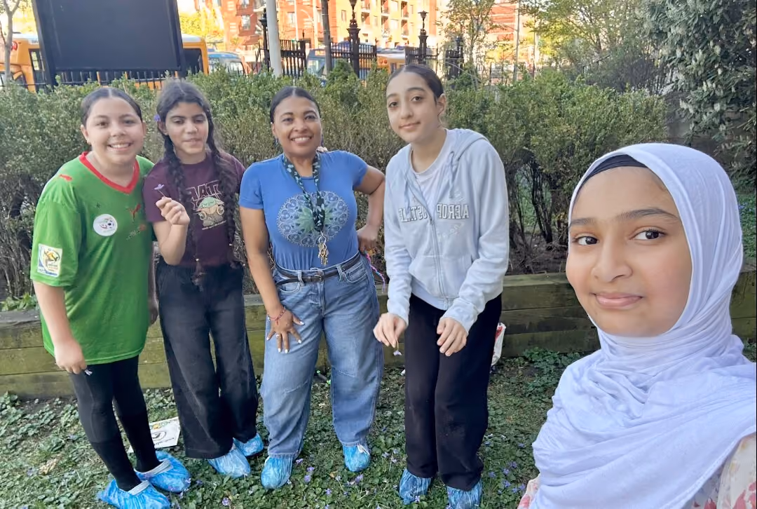 Students and teacher smiling together in school wellness garden