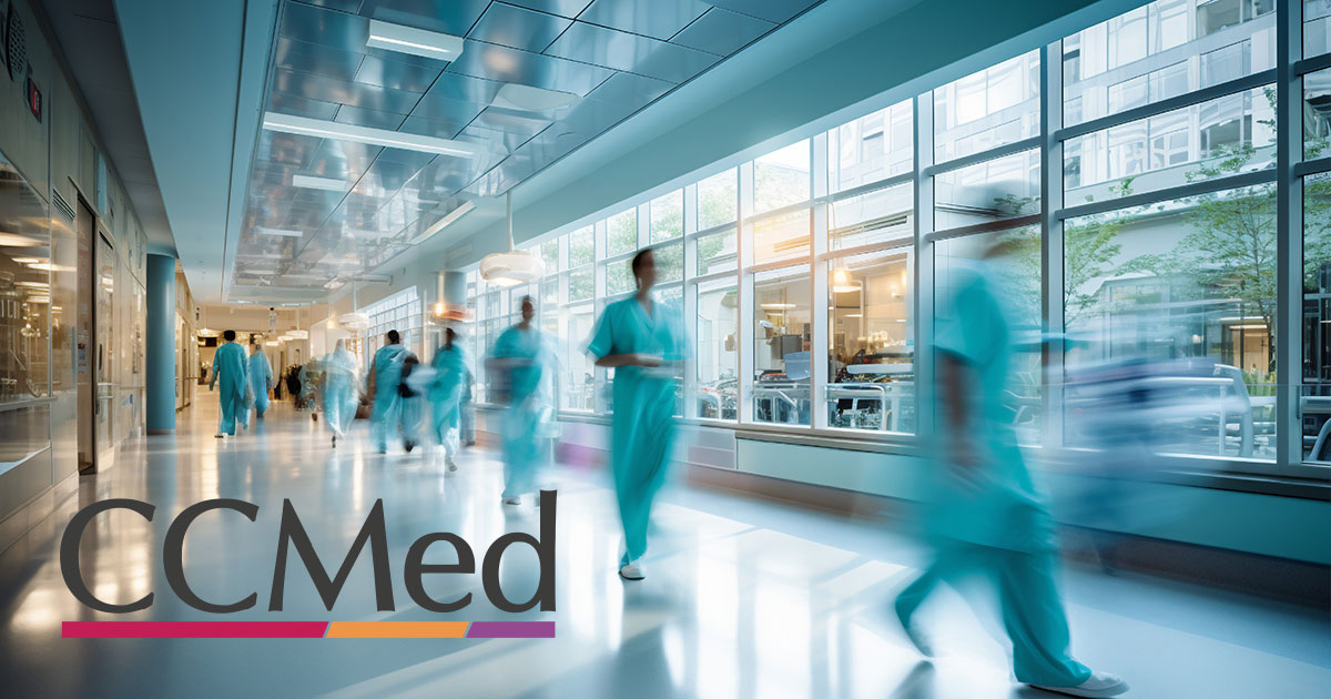 Doctors and nurses in scrubs walk quickly through a hospital hallway.