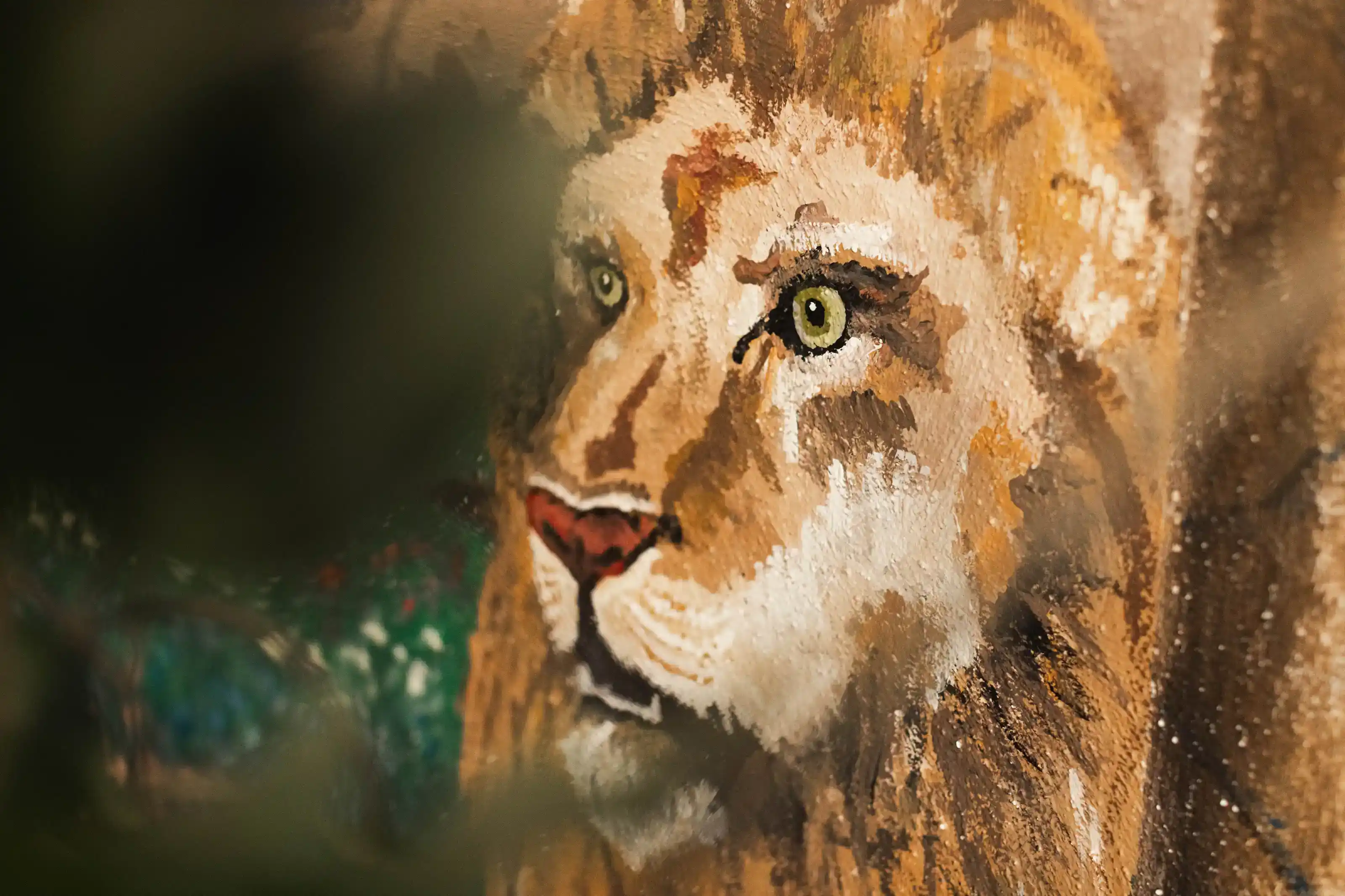 Close-up of a painted lion's face with green eyes and a reddish nose on a textured surface.