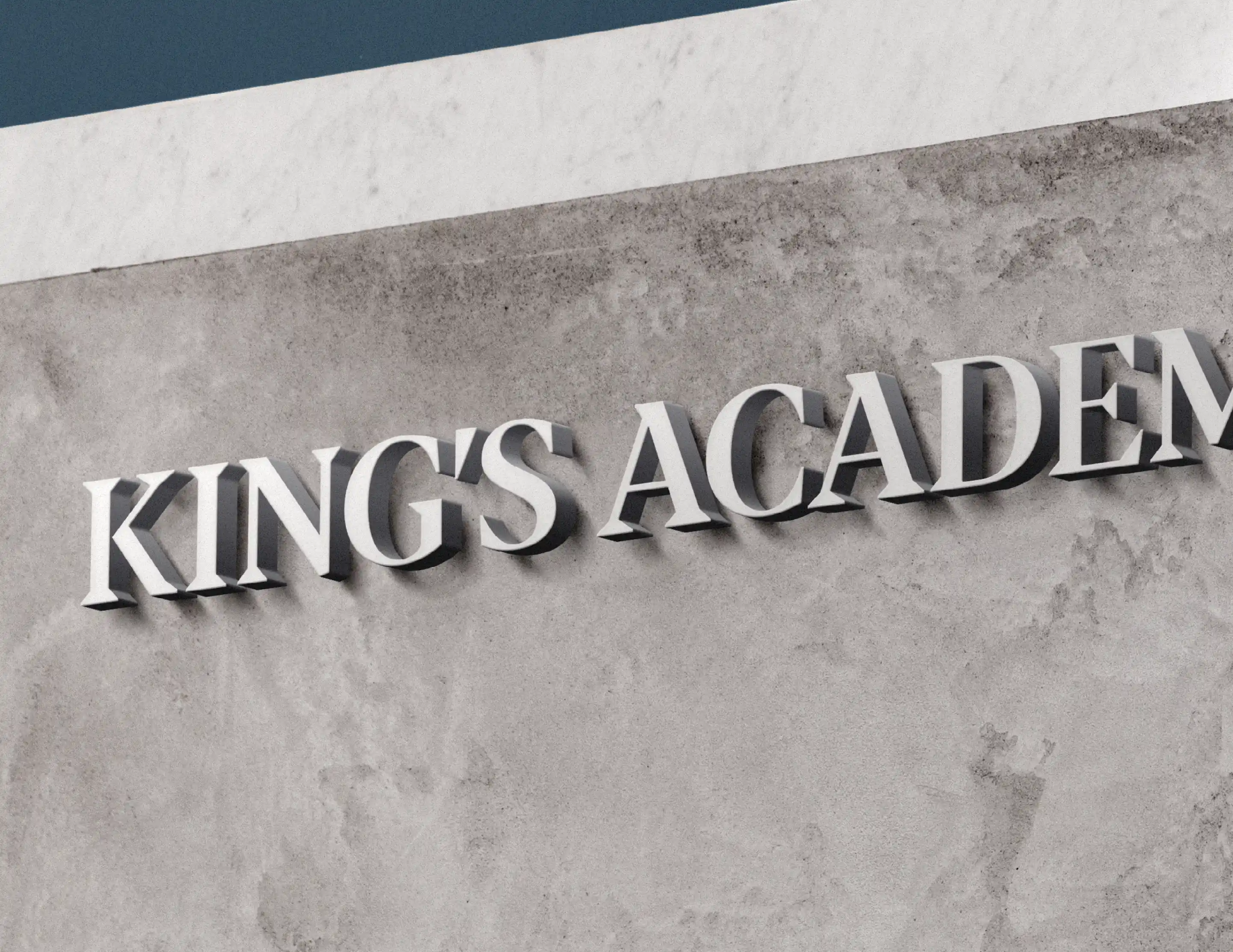 Stone wall with raised white letters spelling 'KING'S ACADEMY' casting shadows.