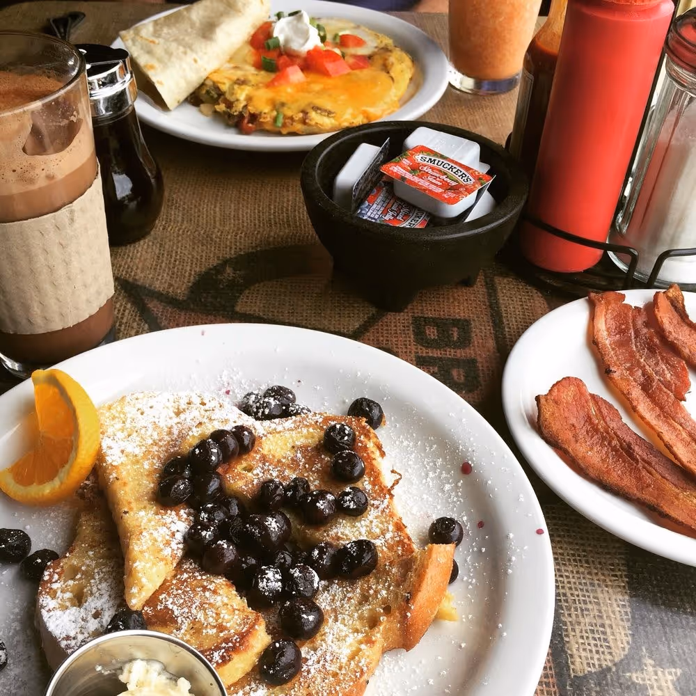 A plate of pancakes with blueberries and whipped cream.