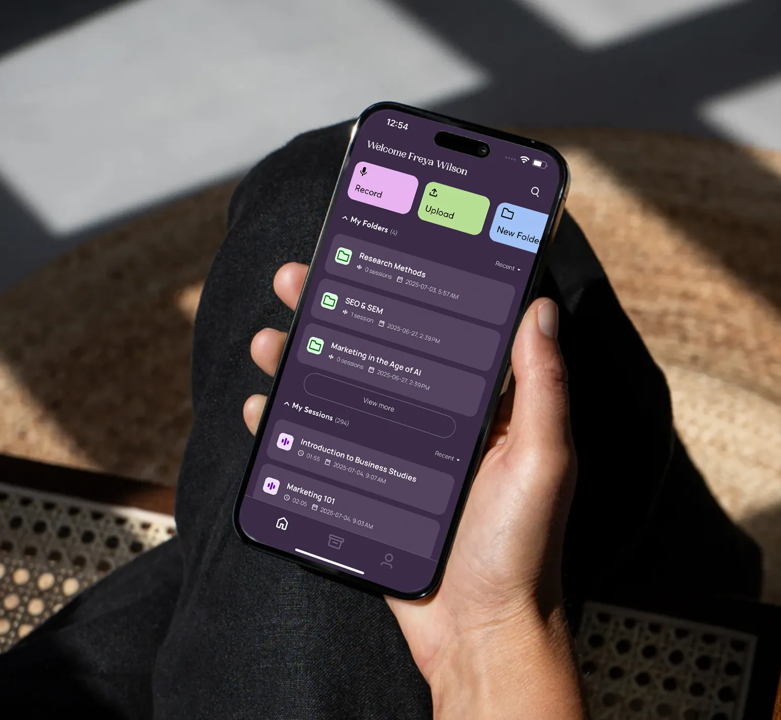 Hand holding smartphone showing a study app with folders and sessions for business and marketing topics.