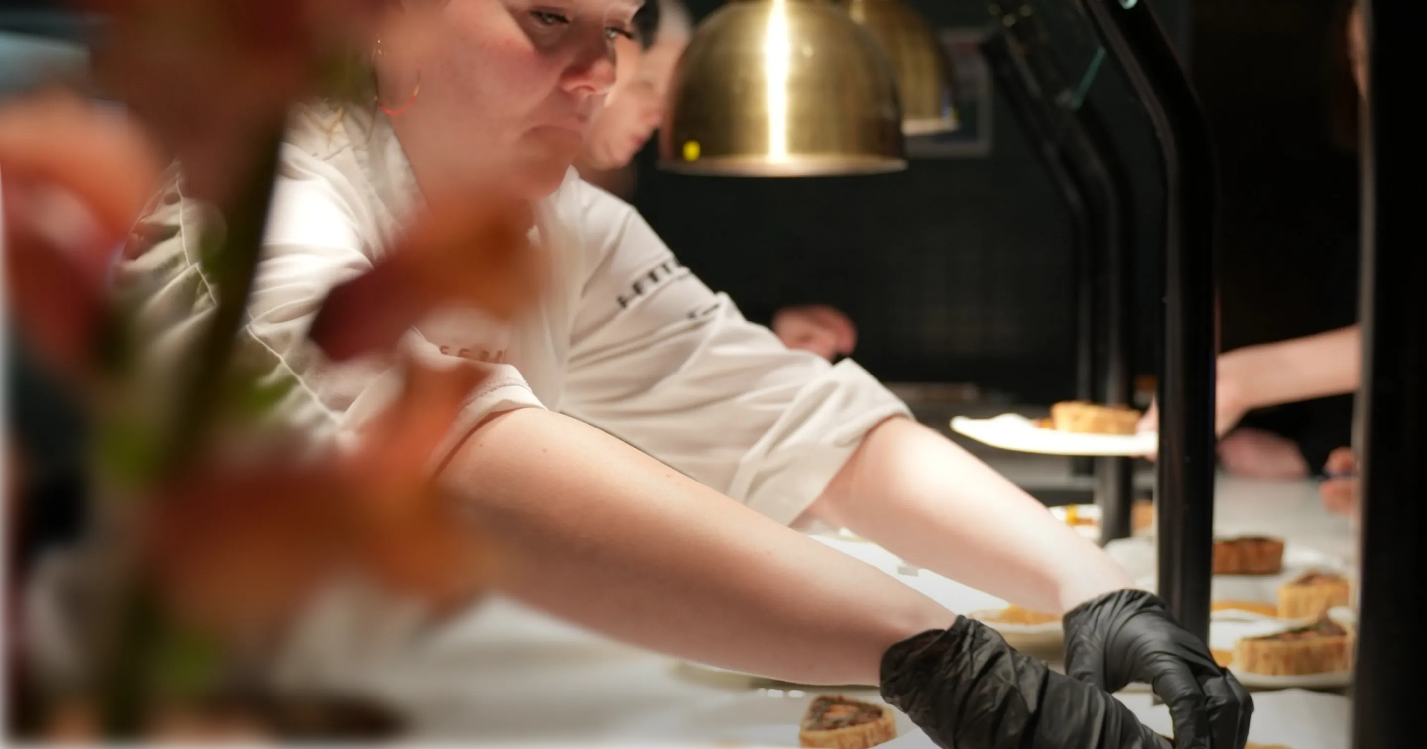 Cheffe en cuisine préparant des plats lors d’un service traiteur illustrant le travail en coulisses et le savoir-faire culinaire