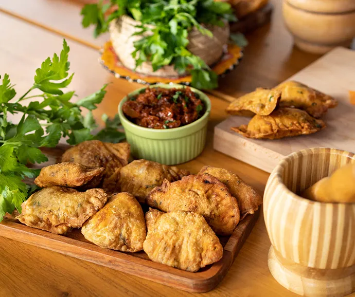 Assortiment de bouchées salées artisanales avec samoussas croustillants et sauces maison présenté sur un buffet traiteur convivial pour événement gourmand.