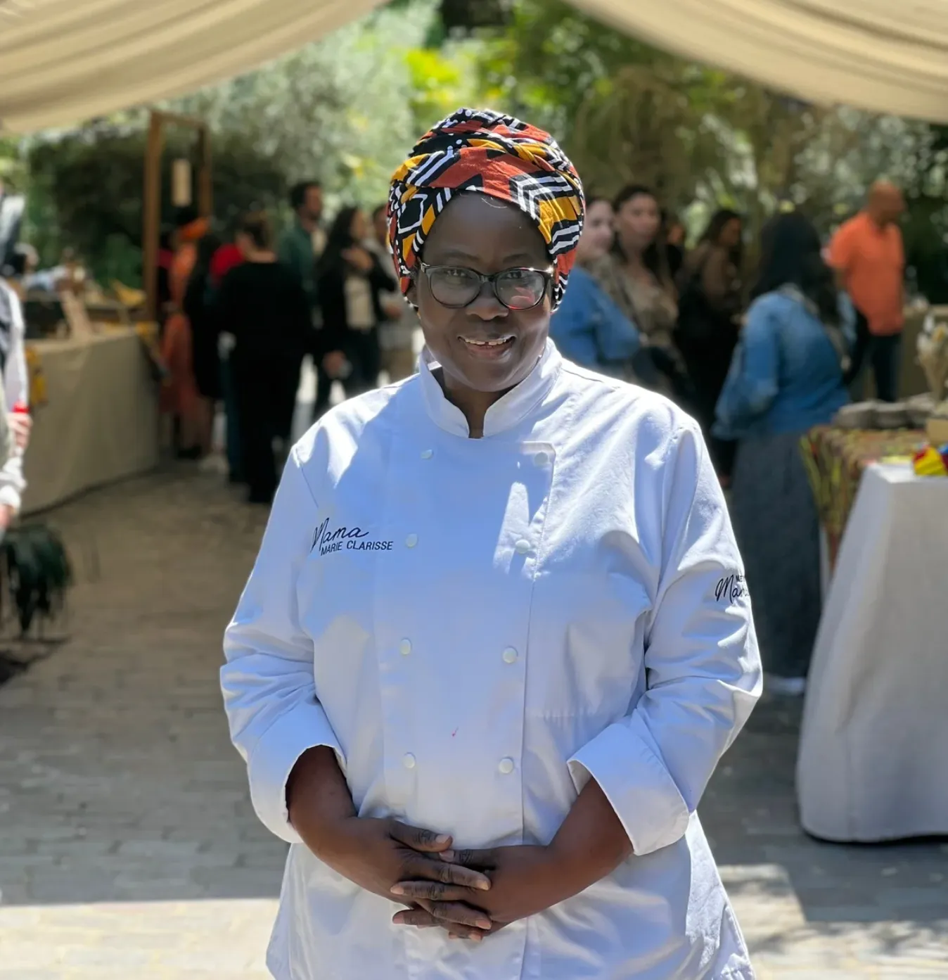 Cheffe traiteur souriante lors d’un événement en extérieur illustrant le savoir-faire culinaire et l’accueil chaleureux