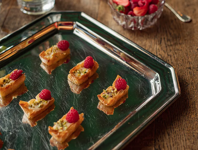 Bouchées sucrées raffinées avec framboises présentées sur plateau traiteur avec dressage élégant
