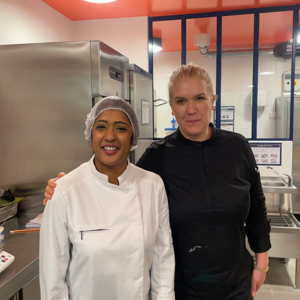 Une table extérieure élégante garnie de fruits frais, légumes de saison, pastèque, agrumes et bouchées apéritives, accompagnée de compositions florales colorées, illustrant une expérience traiteur printanière fraîche et conviviale.