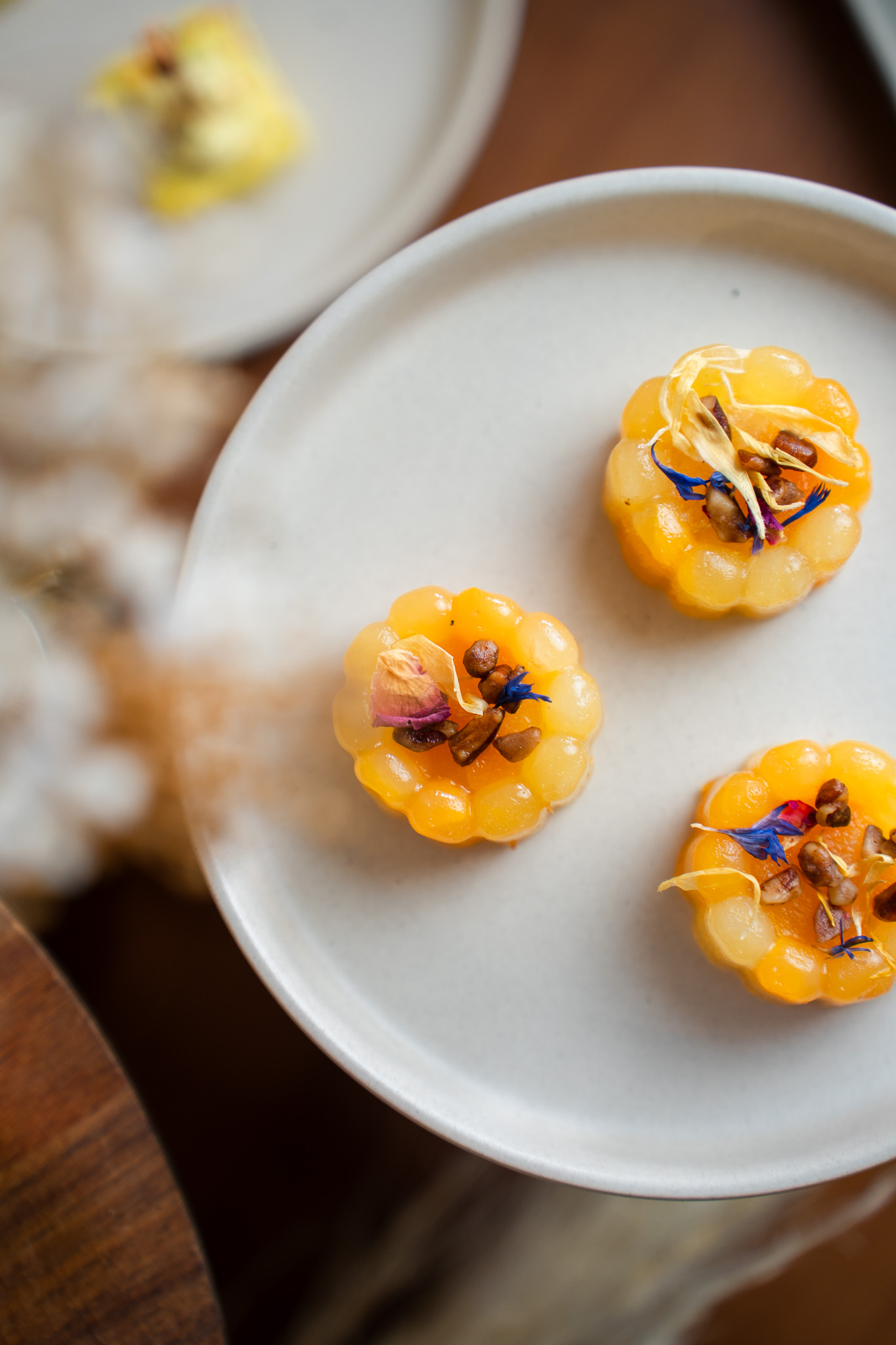 Bouchées dorées garnies de fleurs comestibles sur une assiette blanche