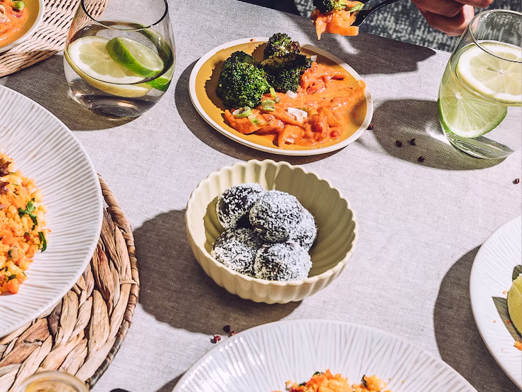 Table dressée avec différents plats colorés, légumes, desserts et boissons au citron dans une ambiance conviviale