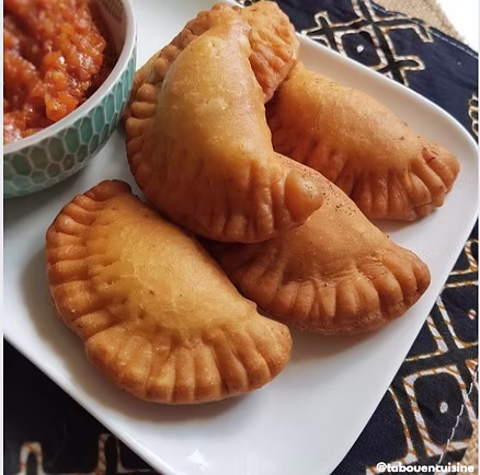 Une cheffe souriante en tenue blanche dresse une table élégante en extérieur avec des amuse-bouches, des plats colorés et des compositions florales, illustrant une expérience traiteur printanière raffinée et conviviale.