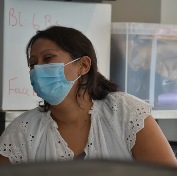 Une cheffe souriante en tenue blanche dresse une table élégante en extérieur avec des amuse-bouches, des plats colorés et des compositions florales, illustrant une expérience traiteur printanière raffinée et conviviale.