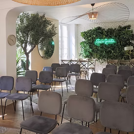 Une cheffe souriante en tenue blanche dresse une table élégante en extérieur avec des amuse-bouches, des plats colorés et des compositions florales, illustrant une expérience traiteur printanière raffinée et conviviale.