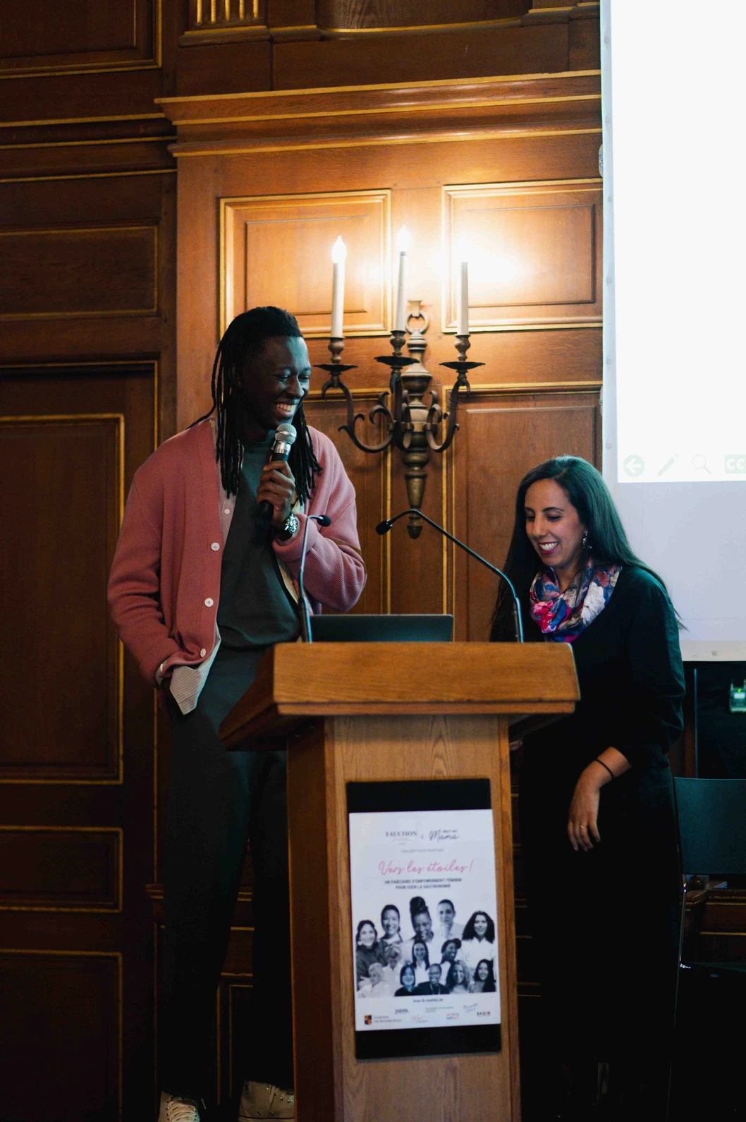 Une table extérieure élégante garnie de fruits frais, légumes de saison, pastèque, agrumes et bouchées apéritives, accompagnée de compositions florales colorées, illustrant une expérience traiteur printanière fraîche et conviviale.