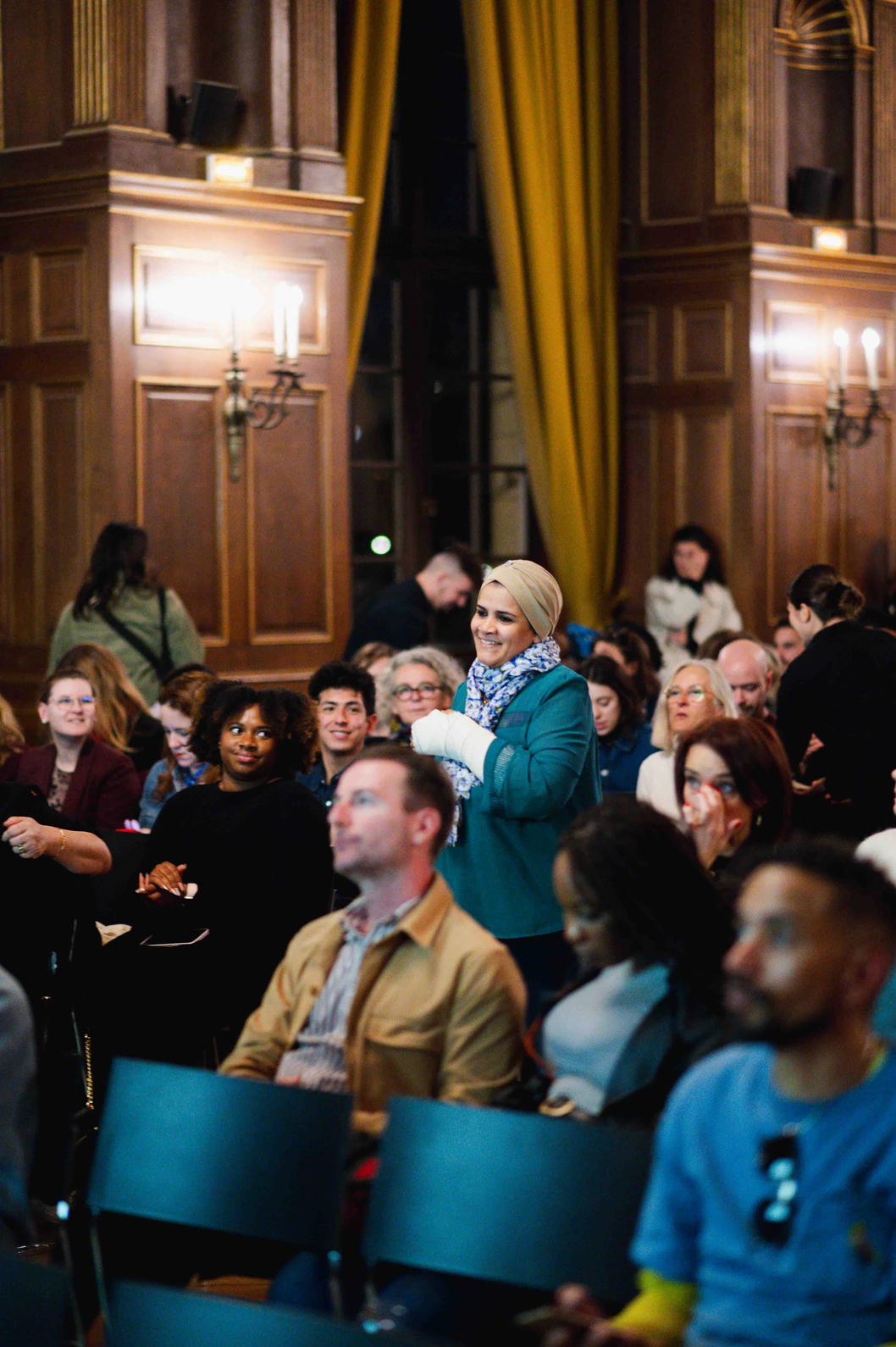 Une cheffe souriante en tenue blanche dresse une table élégante en extérieur avec des amuse-bouches, des plats colorés et des compositions florales, illustrant une expérience traiteur printanière raffinée et conviviale.